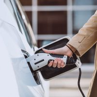 Woman charging electro car at the electric gas station